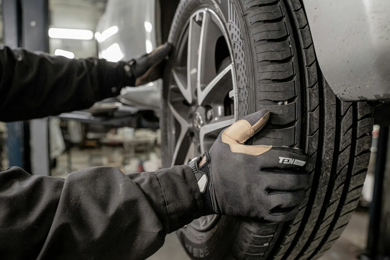 Monteur in handschoenen monteert een band op een lichtmetalen velg in de werkplaats
