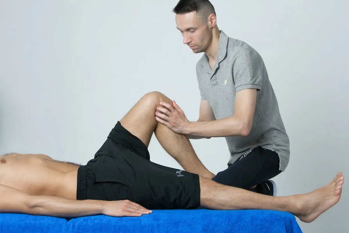 Een fysiotherapeut onderzoekt en behandelt de knie van een patiënt op de behandeltafel