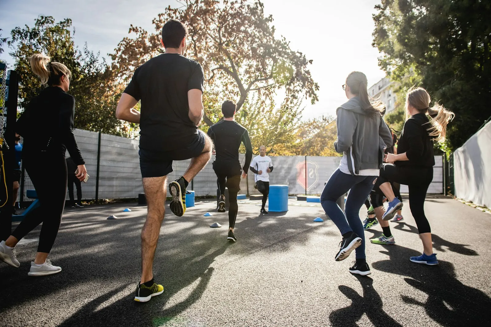 Groep sporters doet een bootcamp-training buiten in de ochtendzon, met hoge knieheffingen