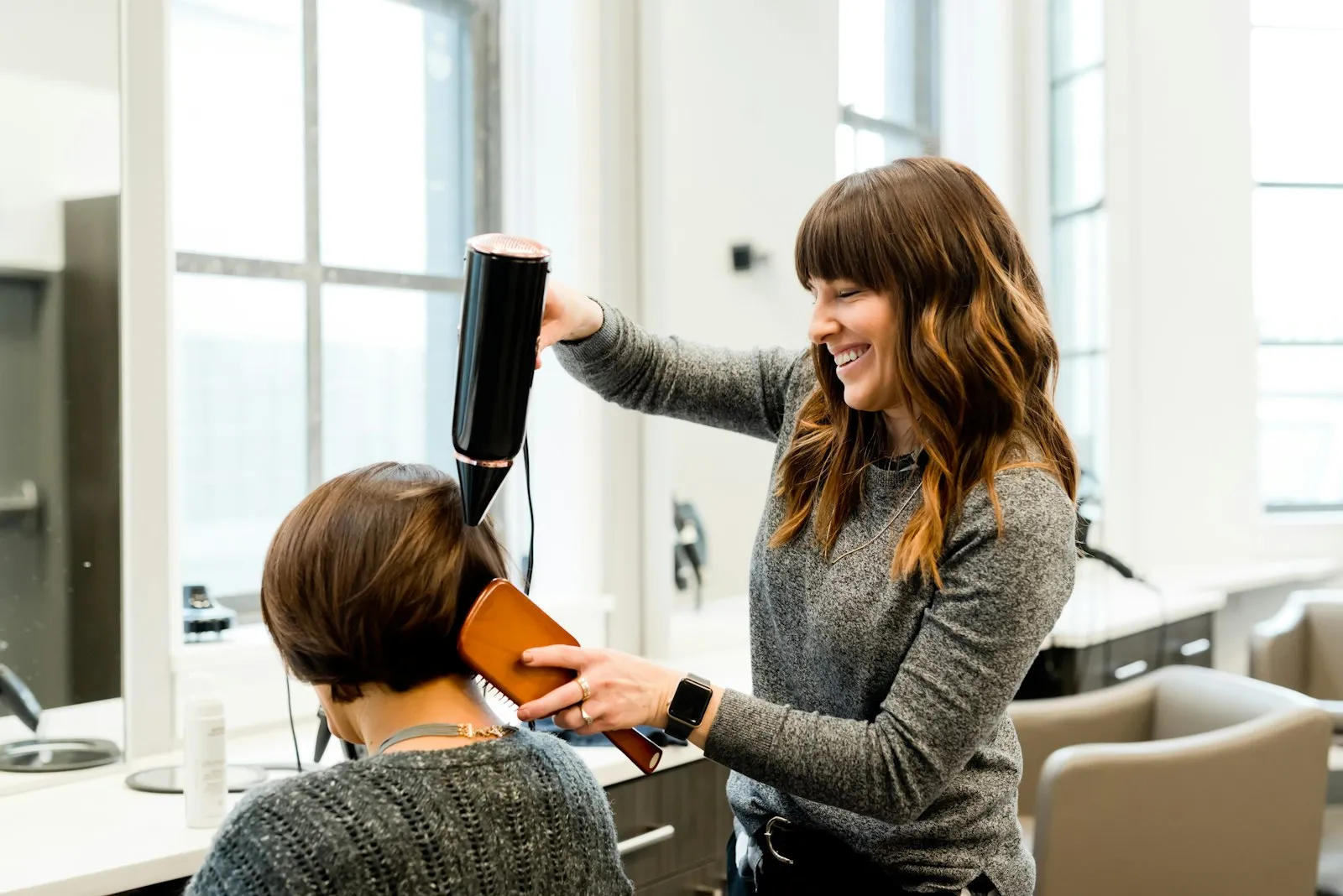 Een klant wordt geföhnd in de lichte salon