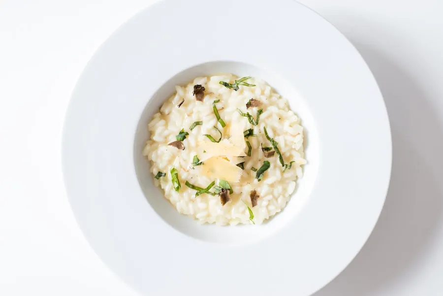 Romige risotto met kaas en kruiden op een wit bord